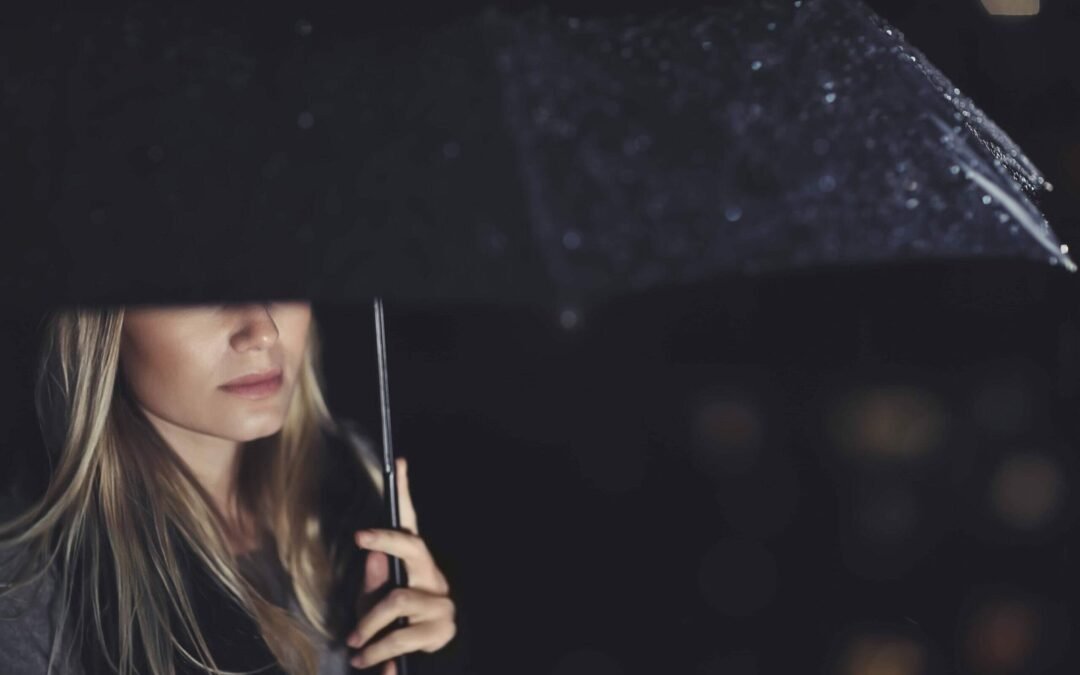 Half face woman under black umbrella on a rainy night